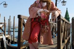 man in carnival costume posing against the backdrop of the gondolas